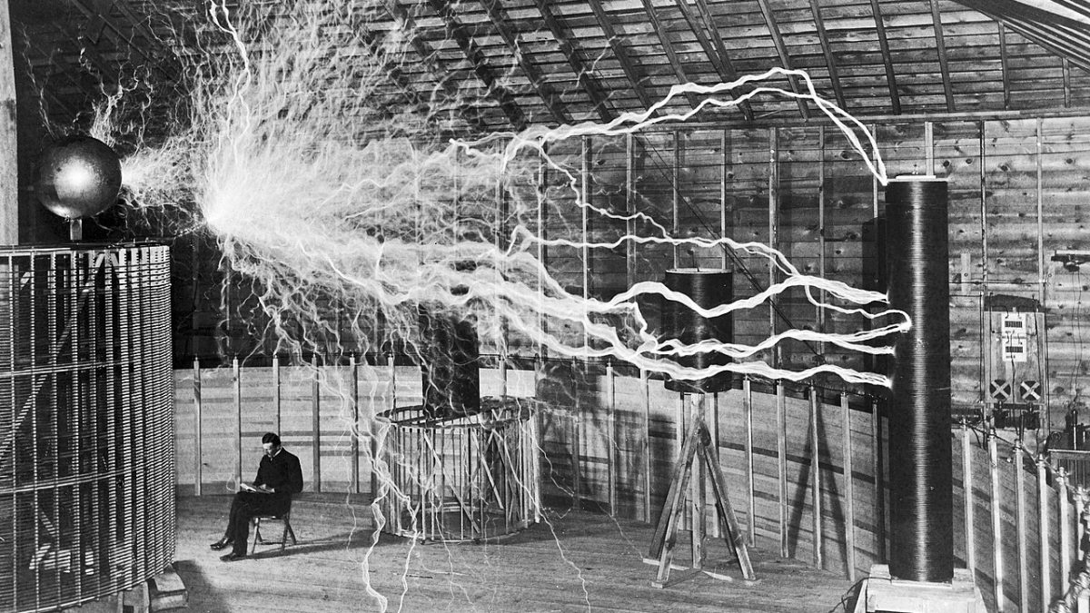 Famous photograph of Serbian-American inventor Nikola Tesla in his laboratory in Colorado Springs December 1899, supposedly sitting reading next to his giant "magnifying transmitte...